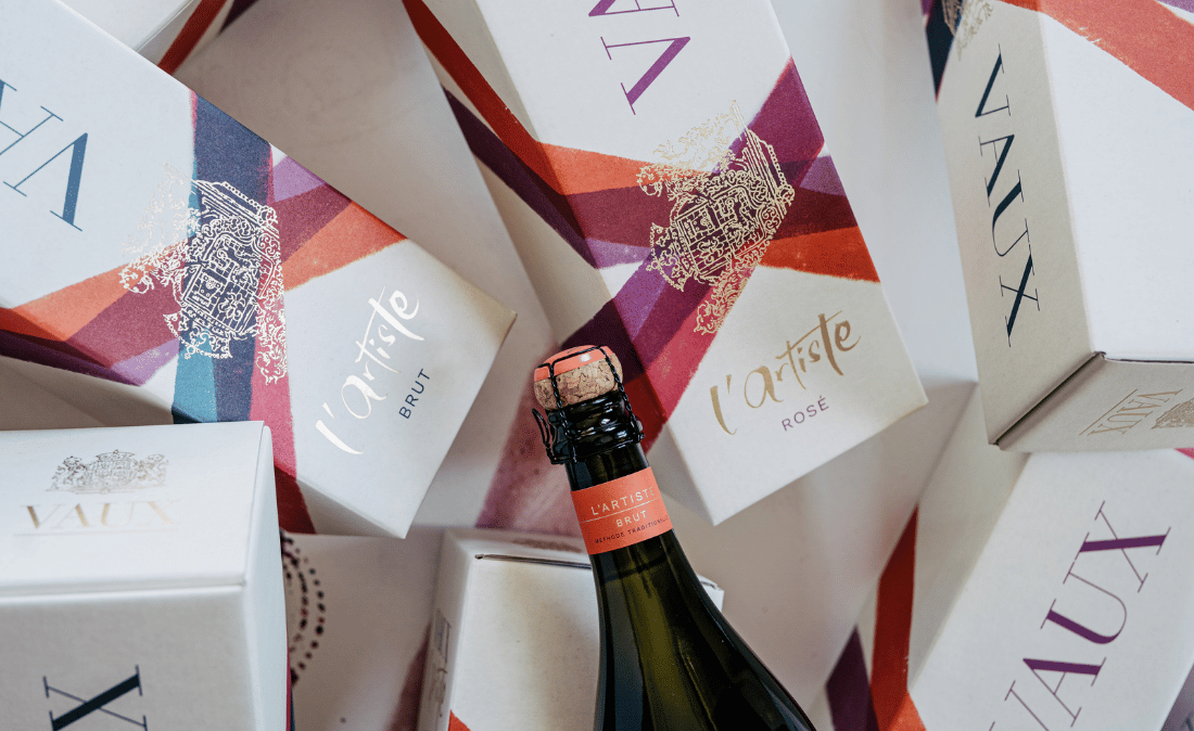 Eine Flasche l´Artiste mit passenden Geschenkkartons im Hintergrund