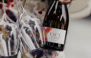 Frau hält seine Flasche l´Artiste Rosé und zwei leere Gläser Sekt in der Hand
