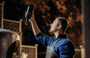 Ein Mann der im Keller steht und eine Flasche in der Hand hoch hält